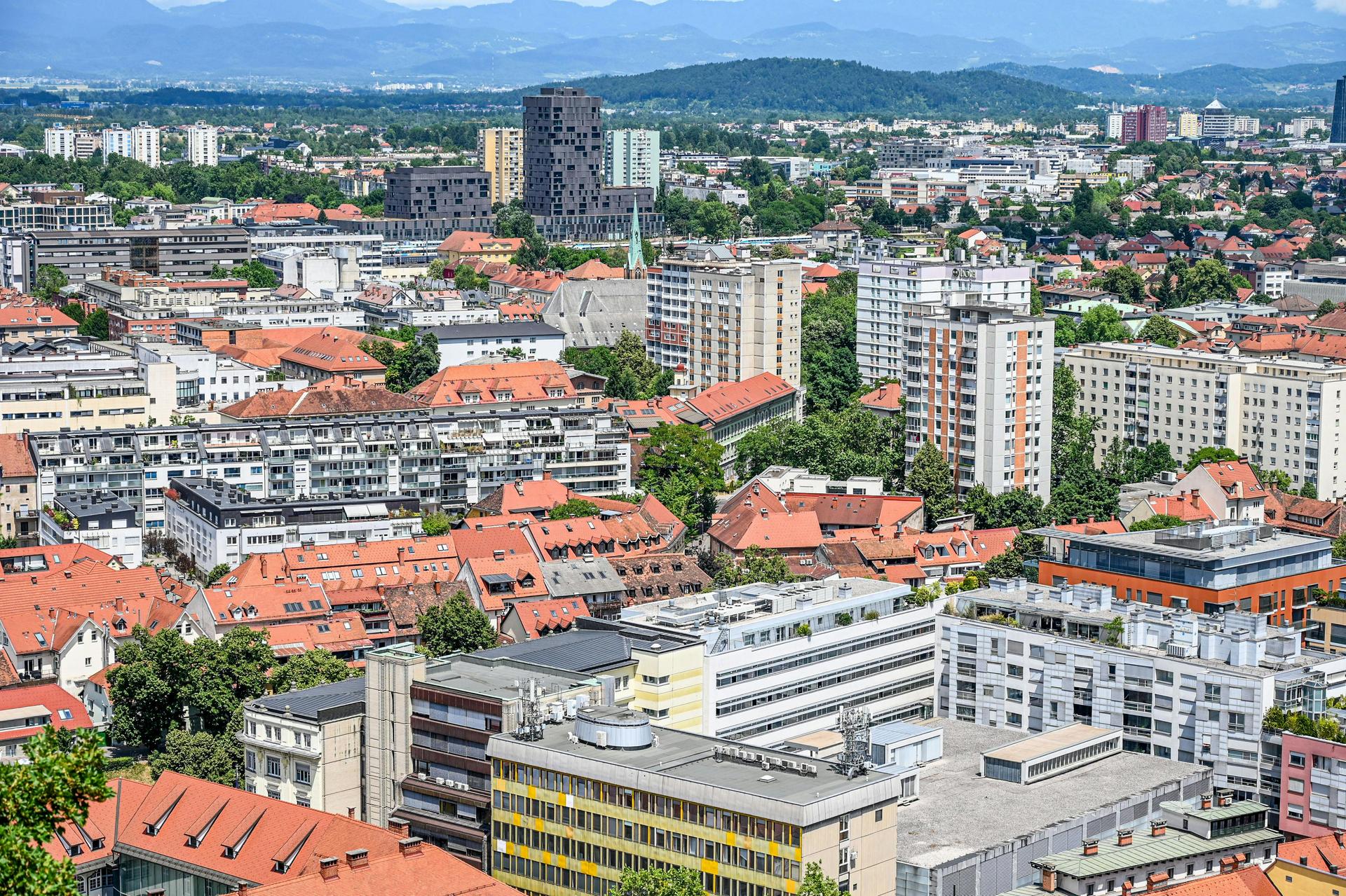 Blick über eine Stadt mit dicht stehenden Wohn- und Bürogebäuden sowie Bergen im Hintergrund